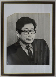 大江健三郎肖像写真額　モノクロ　裏面に文藝春秋のゴム印有　写真３０４×２５４ミリ　四方角にテープ跡有　左上欠有