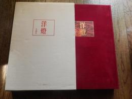 洋燈　深沢幸雄  [限定版]
藤川清撮影 ; 加藤孝次,由水常雄著
    出版社 冬樹社
    刊行年 昭和52年
    ページ数 129頁
    サイズ 21×30×3㎝ 
灯火用ガラス、とりわけランプの油壷とホヤの製造は明治のガラス工業をささえる主要分野であった。石油ランプは明治前期に急速に普及し生活の必需品となっていった。　　　　　　　　　　　　　　　　　中でも座敷ランプは、行灯や燭台のスタイルを取り入れ和洋折衷の魅力に富んでいる。また材質も鋳鉄製、朱塗り、安価なブリキ製など多様である。舶来品に匹敵するランプの制作は、明治中期以降で畳や障子に似合う日本的たおやかさを身につけた作例が生まれた。　　　　　　　　　　　　　　　　座敷ランプは、渋みとガラスの優雅さが不思議な調和をたもつ小世界を作り出す和ガラスの代表といえます。笠や油壷にガラスの加飾の粋が凝らされた卓上に置くランプ卓上に置く石油ランプ（灯油ランプ）を総称して「台ランプ」と呼びます。その中でも平芯で笠をかけない四つ爪で丸ホヤを支えたランプを「置きランブ」とし二分四つ手・五分四つ手とも呼び、巻芯のアルガン燈で円筒形の竹ホヤを冠せて笠のかかったものを「台ランプ」と区分します。笠や油壷にガラス加飾の粋が凝らされた華麗な作例が多い。座敷生活が一般的だった明治期には、紫檀や花凛、それを模した材質のランプ台が用意されることもあった。　豆ランプ。小型のランプは、仏壇、神棚、台所、風呂場、便所などに運ばれて手元を照らす明かりにされました。豆ランプ、手ランプ、吊りランプは巻き芯を用いる。大正４年の佐々木硝子店のカタログには同様の豆ランプは「豆押台」と掲載されている。　　　　　　　　
