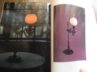 洋燈　深沢幸雄  [限定版]
藤川清撮影 ; 加藤孝次,由水常雄著
    出版社 冬樹社
    刊行年 昭和52年
    ページ数 129頁
    サイズ 21×30×3㎝ 
灯火用ガラス、とりわけランプの油壷とホヤの製造は明治のガラス工業をささえる主要分野であった。石油ランプは明治前期に急速に普及し生活の必需品となっていった。　　　　　　　　　　　　　　　　　中でも座敷ランプは、行灯や燭台のスタイルを取り入れ和洋折衷の魅力に富んでいる。また材質も鋳鉄製、朱塗り、安価なブリキ製など多様である。舶来品に匹敵するランプの制作は、明治中期以降で畳や障子に似合う日本的たおやかさを身につけた作例が生まれた。　　　　　　　　　　　　　　　　座敷ランプは、渋みとガラスの優雅さが不思議な調和をたもつ小世界を作り出す和ガラスの代表といえます。笠や油壷にガラスの加飾の粋が凝らされた卓上に置くランプ卓上に置く石油ランプ（灯油ランプ）を総称して「台ランプ」と呼びます。その中でも平芯で笠をかけない四つ爪で丸ホヤを支えたランプを「置きランブ」とし二分四つ手・五分四つ手とも呼び、巻芯のアルガン燈で円筒形の竹ホヤを冠せて笠のかかったものを「台ランプ」と区分します。笠や油壷にガラス加飾の粋が凝らされた華麗な作例が多い。座敷生活が一般的だった明治期には、紫檀や花凛、それを模した材質のランプ台が用意されることもあった。　豆ランプ。小型のランプは、仏壇、神棚、台所、風呂場、便所などに運ばれて手元を照らす明かりにされました。豆ランプ、手ランプ、吊りランプは巻き芯を用いる。大正４年の佐々木硝子店のカタログには同様の豆ランプは「豆押台」と掲載されている。　　　　　　　　
