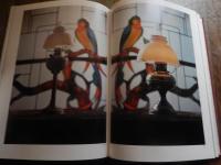 洋燈　深沢幸雄  [限定版]
藤川清撮影 ; 加藤孝次,由水常雄著
    出版社 冬樹社
    刊行年 昭和52年
    ページ数 129頁
    サイズ 21×30×3㎝ 
灯火用ガラス、とりわけランプの油壷とホヤの製造は明治のガラス工業をささえる主要分野であった。石油ランプは明治前期に急速に普及し生活の必需品となっていった。　　　　　　　　　　　　　　　　　中でも座敷ランプは、行灯や燭台のスタイルを取り入れ和洋折衷の魅力に富んでいる。また材質も鋳鉄製、朱塗り、安価なブリキ製など多様である。舶来品に匹敵するランプの制作は、明治中期以降で畳や障子に似合う日本的たおやかさを身につけた作例が生まれた。　　　　　　　　　　　　　　　　座敷ランプは、渋みとガラスの優雅さが不思議な調和をたもつ小世界を作り出す和ガラスの代表といえます。笠や油壷にガラスの加飾の粋が凝らされた卓上に置くランプ卓上に置く石油ランプ（灯油ランプ）を総称して「台ランプ」と呼びます。その中でも平芯で笠をかけない四つ爪で丸ホヤを支えたランプを「置きランブ」とし二分四つ手・五分四つ手とも呼び、巻芯のアルガン燈で円筒形の竹ホヤを冠せて笠のかかったものを「台ランプ」と区分します。笠や油壷にガラス加飾の粋が凝らされた華麗な作例が多い。座敷生活が一般的だった明治期には、紫檀や花凛、それを模した材質のランプ台が用意されることもあった。　豆ランプ。小型のランプは、仏壇、神棚、台所、風呂場、便所などに運ばれて手元を照らす明かりにされました。豆ランプ、手ランプ、吊りランプは巻き芯を用いる。大正４年の佐々木硝子店のカタログには同様の豆ランプは「豆押台」と掲載されている。　　　　　　　　
